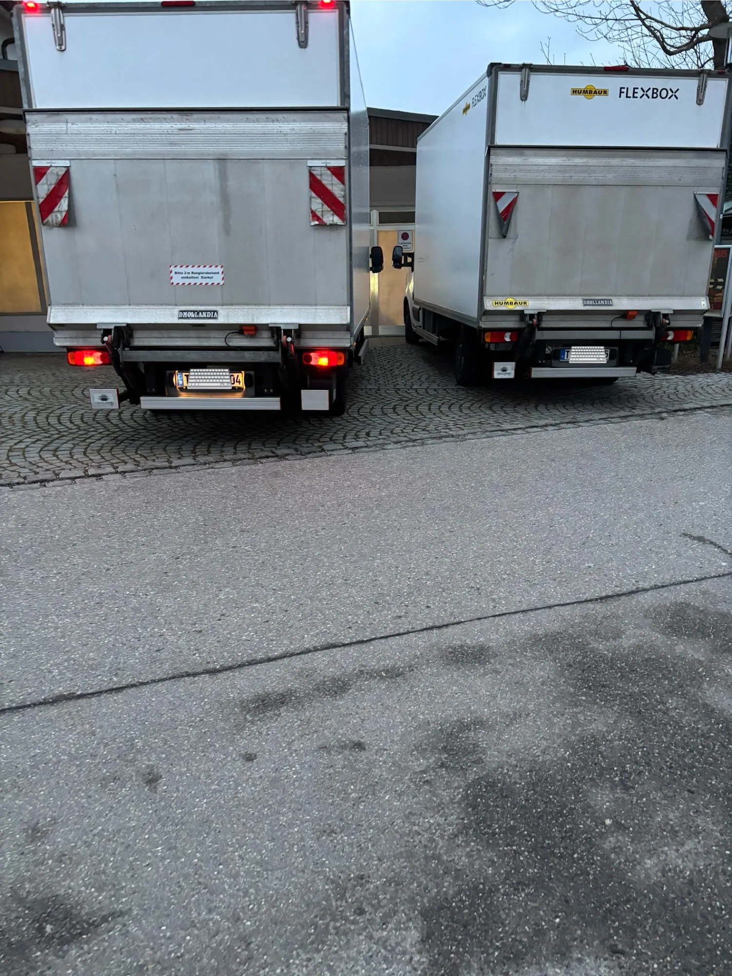 Zwei Ac.Umzugtransport Kofferfahrzeuge nebeneinander mit geöffneter Ladebordwand